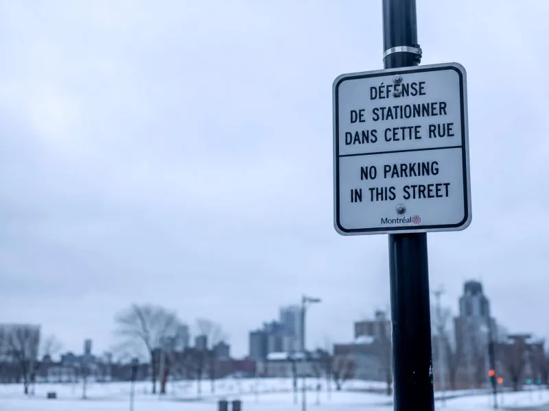 A bilingual street sign in Montréal, French above English, on an overcast winter day.